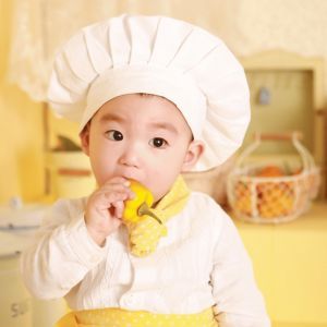 Toddler eating bell pepper dressed as a Tiny Chef