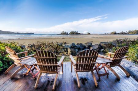 4 Adirondack chairs on a deck overlooking a beach