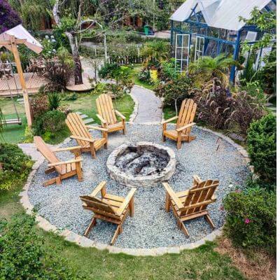Adirondack chairs around a fire pit in a backyard garden