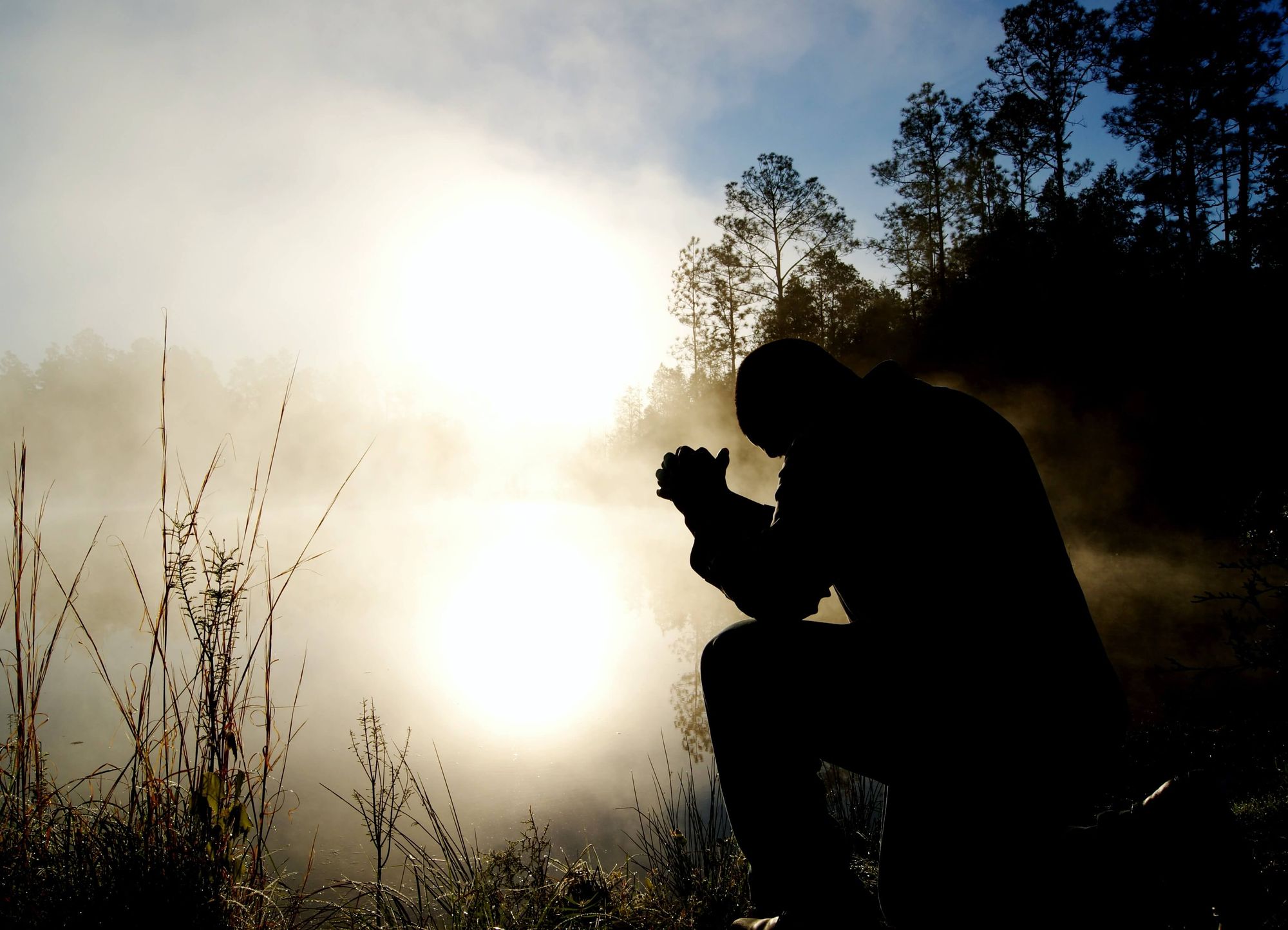 Man on knees in morning mist praying