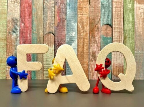 3 little stickmen holding up the letters FAQ with colored wood background