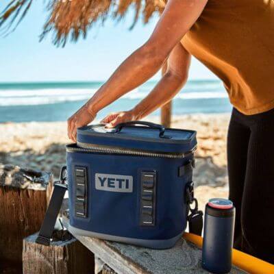 Man at beach setting opening the Yeti soft cooler