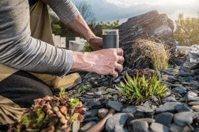 Man placing small area light in a rock garden with herbs